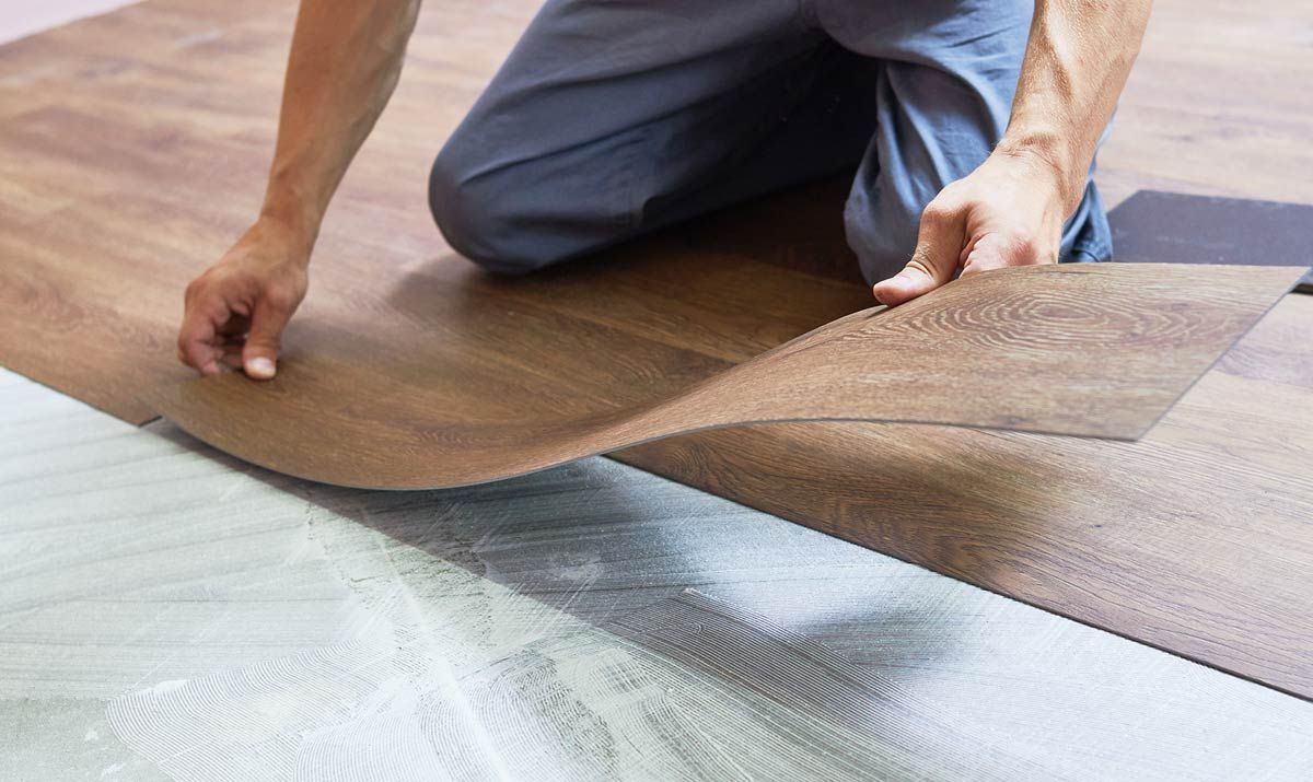 Flooring installer laying down laminate wood flooring