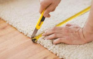 man cutting carpet over laminate flooring