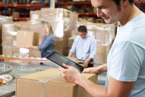 man using erp software on table to track inventory inside warehouse